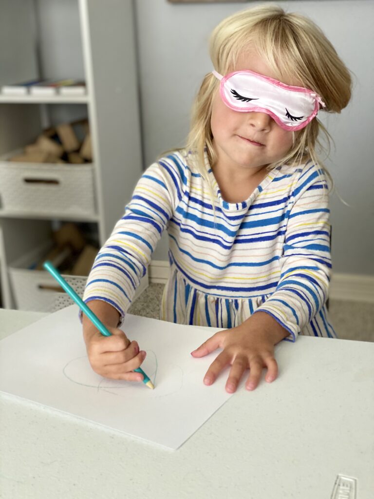 Child makes marks while closing eyes