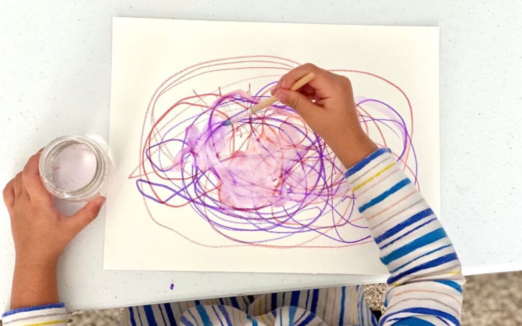 Child makes marks and uses water to explore what happens