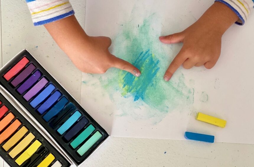 Child using fingers to blend soft pastel on paper