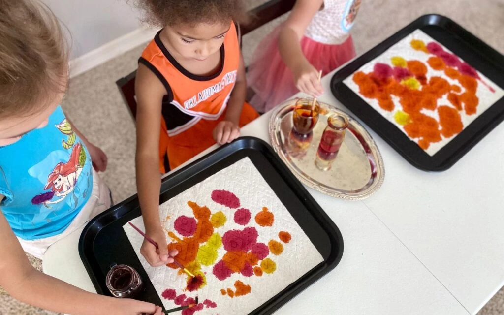 Child spreading liquid water color paint on paper towel