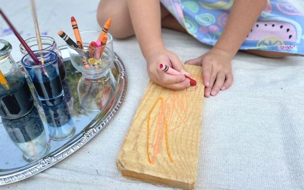 Child drawing with a crayon on piece of wood