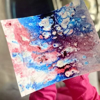 Child holding art experiment with oil and water color