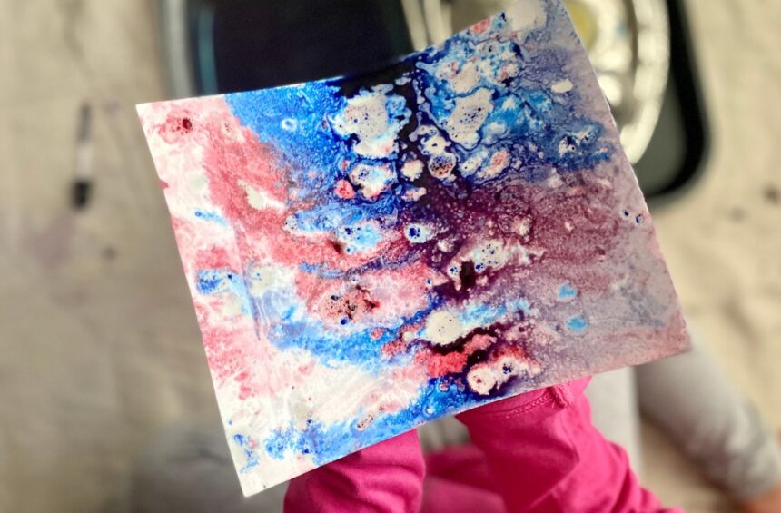 Child holding art experiment with oil and water color