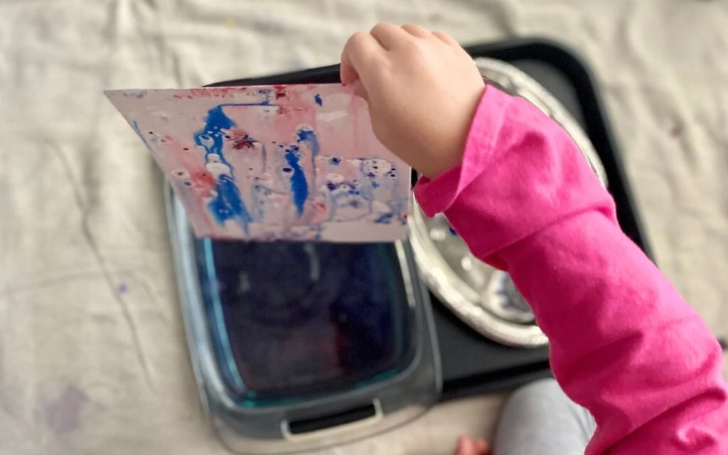 Child holding art experiment with oil and water color