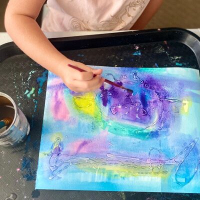 Child painting over dried glue