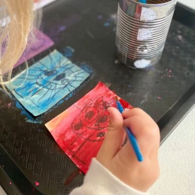Child painting sticker with watercolor over sharpie drawing