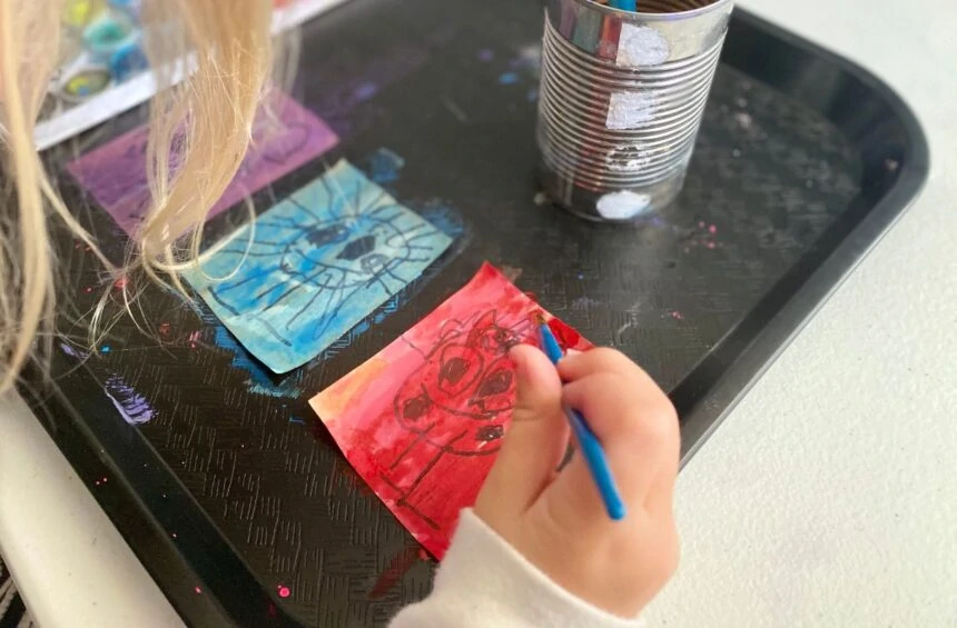 Child painting sticker with watercolor over sharpie drawing