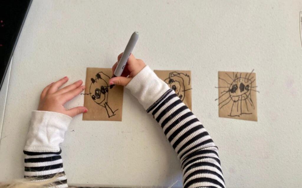 Child drawing with sharpies on sticker paper