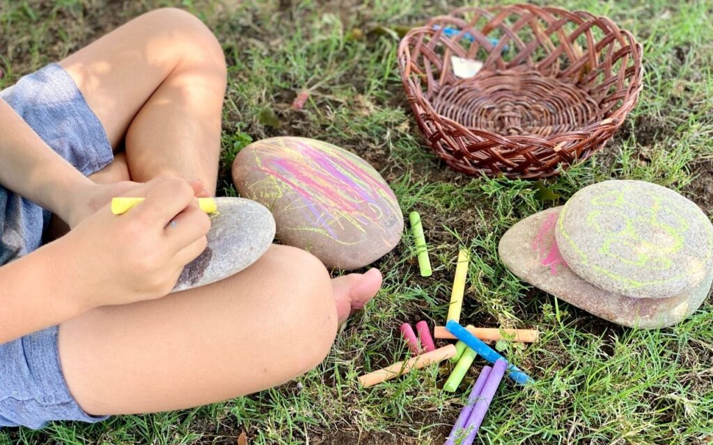 Child drawing on large flat rocks with chalk