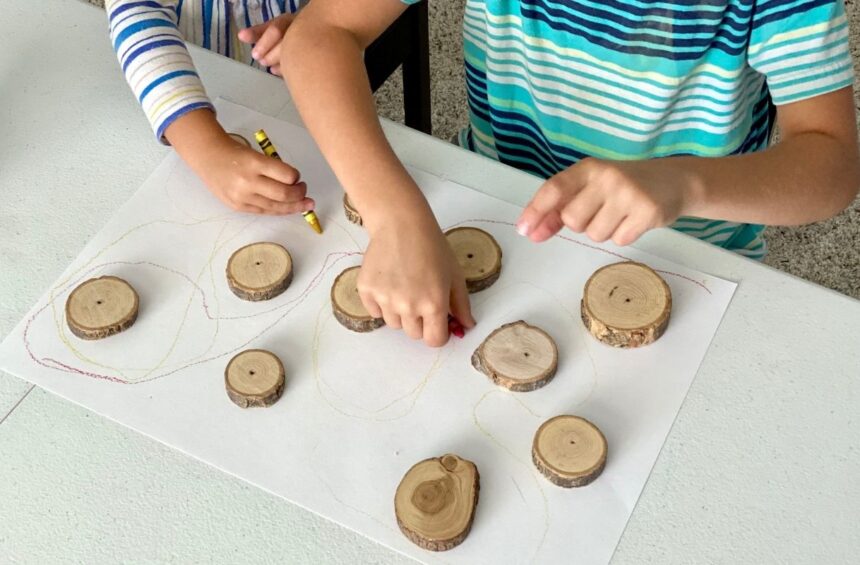 Children drawing marks around wood cookies on paper