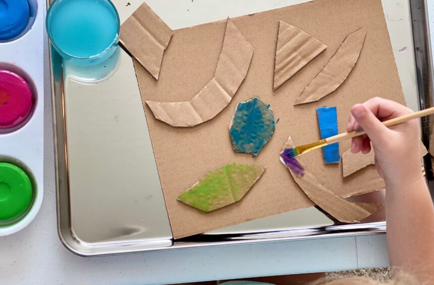 Child painting cardboard shapes