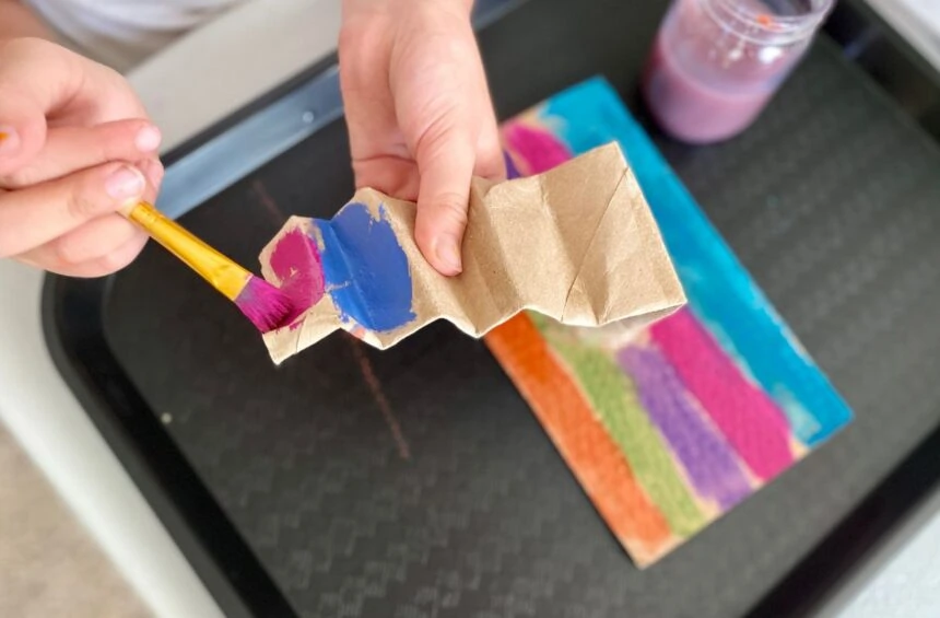 Child painting cardboard tubes glued to a cardboard base