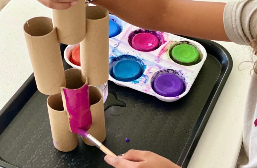 Child painting paper tubes built up like a sculpture
