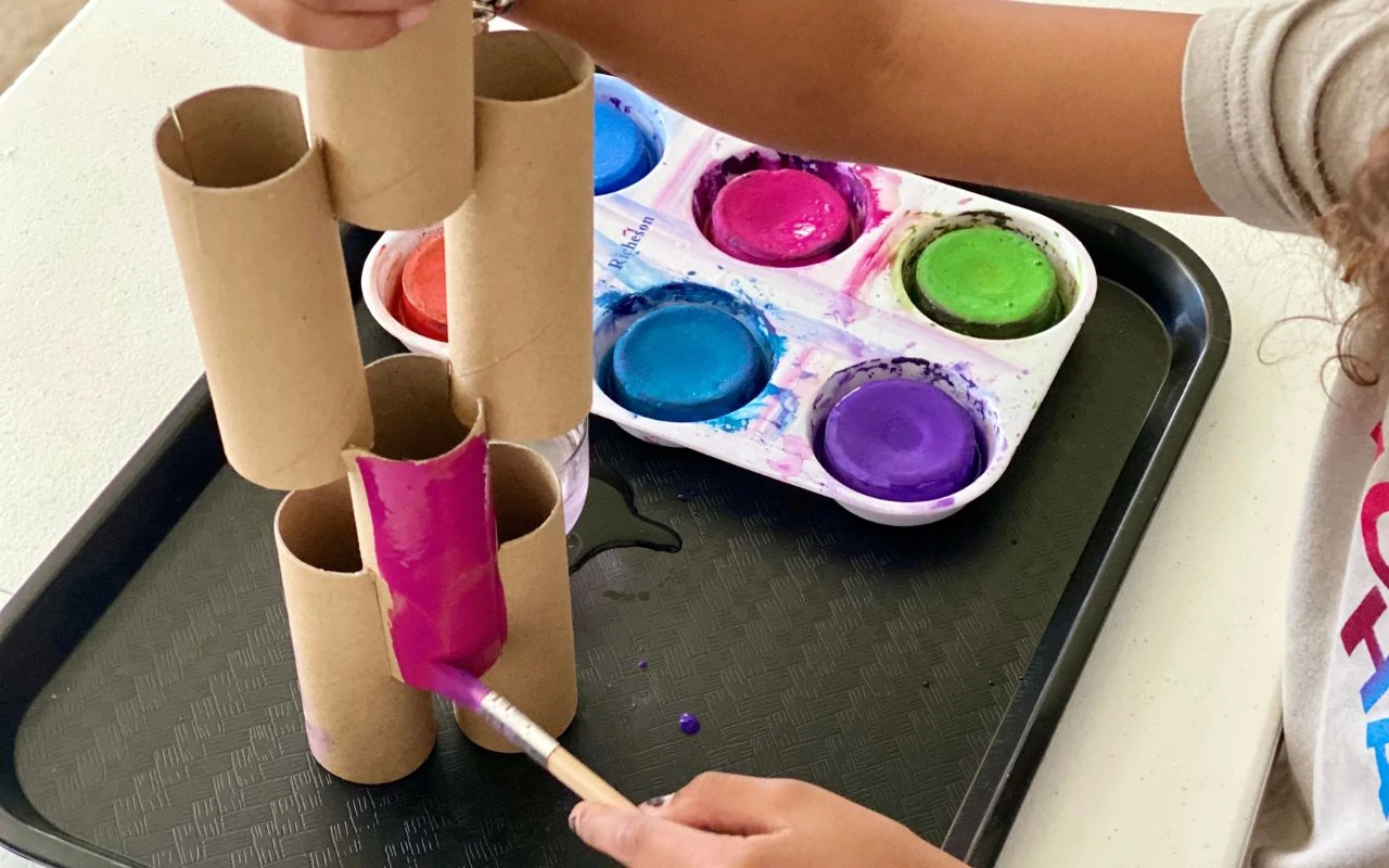 Child painting paper tubes built up like a sculpture