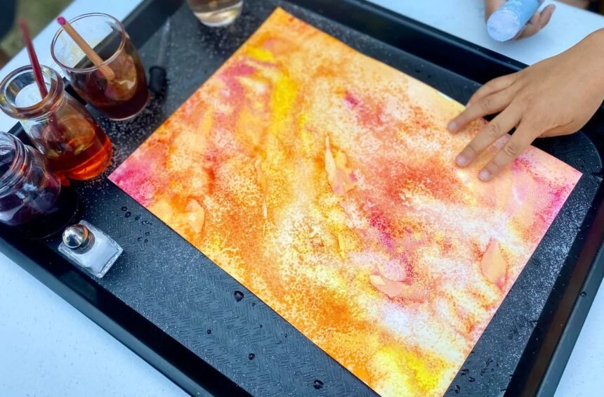 Child adding salt to their painting