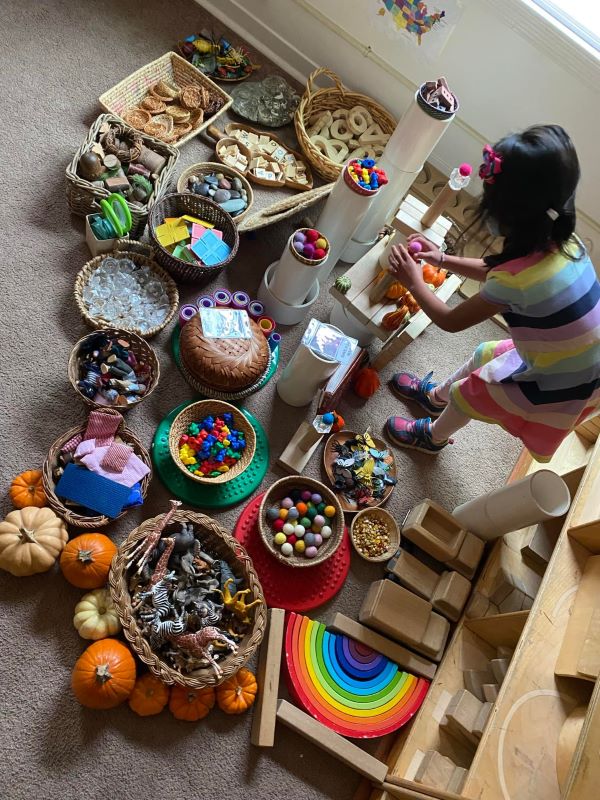 child playing with baskets of loose parts