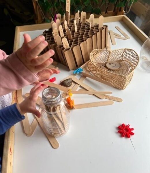 child hands playing with wooden popsicle sticks