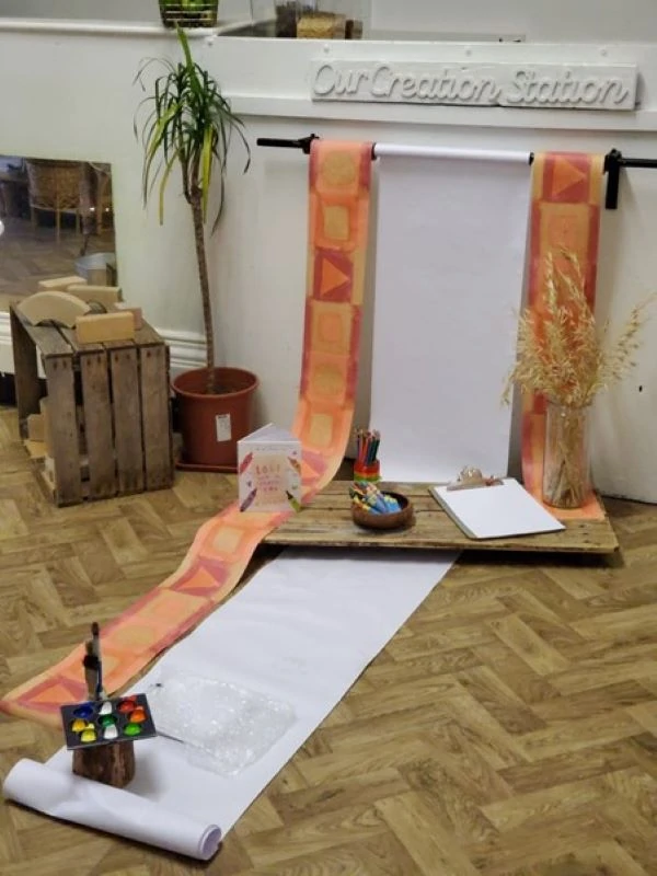 Roll of paper draped from the wall to the floor painting play invitation
