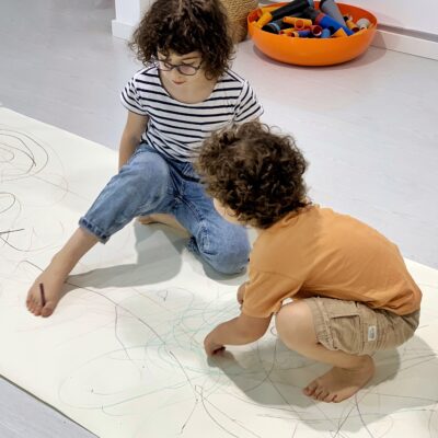 Two children Drawing Movement over a large piece of paper