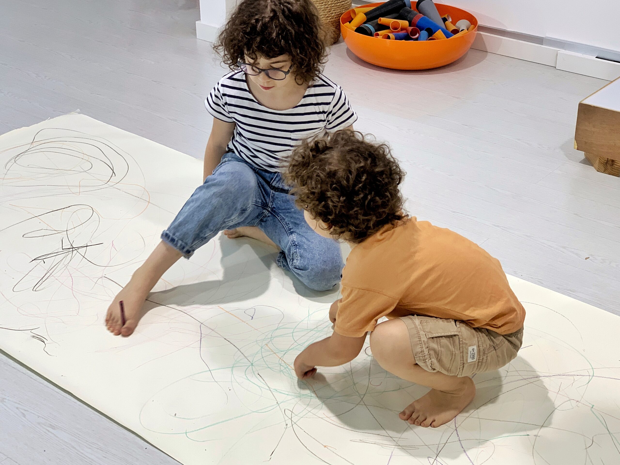 Two children Drawing Movement over a large piece of paper