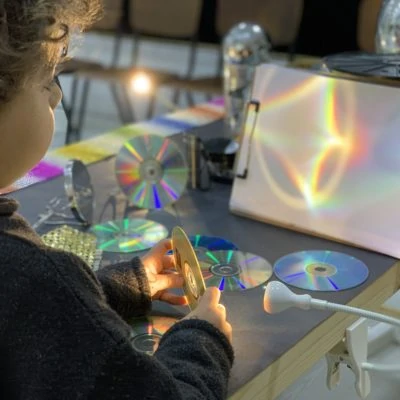 Young child holding a CD and exploring reflection and color