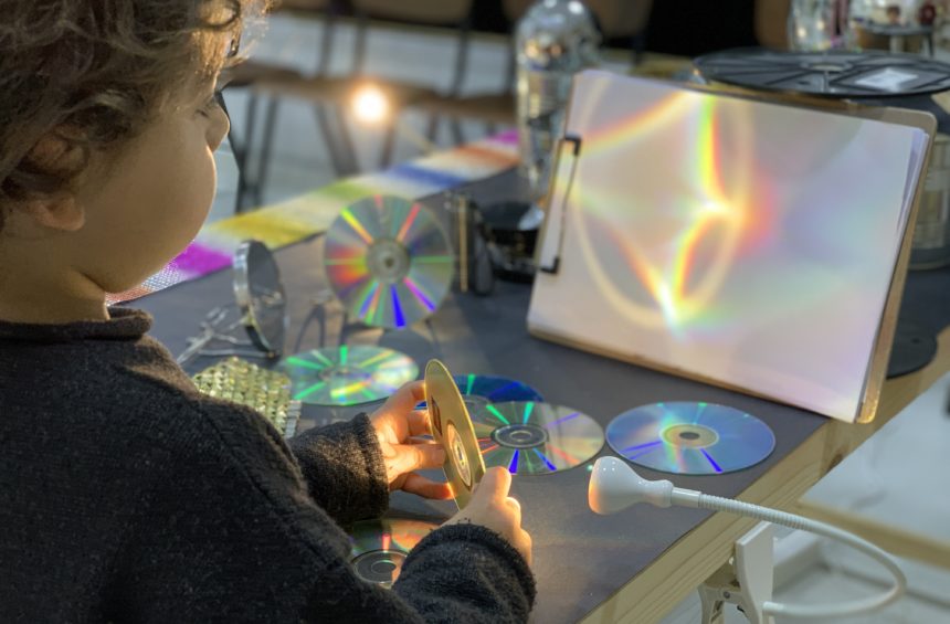Young child holding a CD and exploring reflection and color